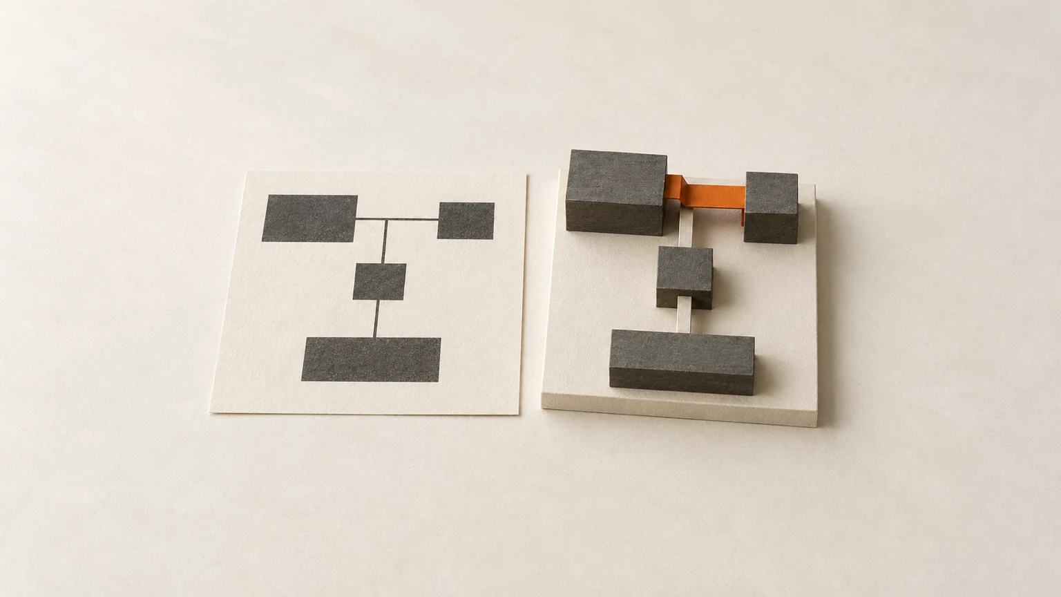 A flat paper plan beside a card-and-graphite model built from it, where one orange piece fills a gap the plan did not show.